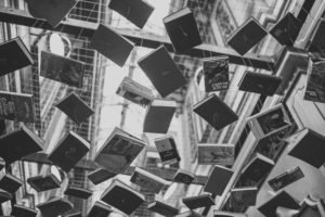 Black-and-white photo of books hanging from a glass ceiling by pieces of thick string.