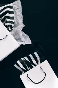 Two white gift bags with black and white tissue paper sticking out of them. 