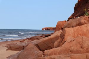 Red rocks, dirt, and sand on a Prince Edward Island beach. 