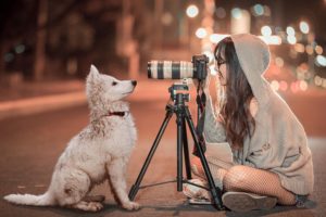 Person photographing her white dog. 