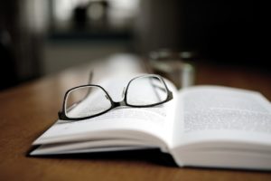 A pair of black-rimmed glasses lying on an opened book. 