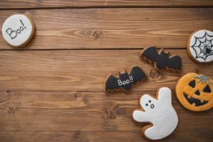 Sugar cutout cookies decorated to look like a ghost, bats, spider web, the word “boo,” and a jack-o-lantern. 