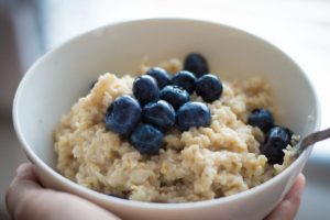 A white bowl filled with oatmeal and blueberries. 