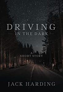 Driving in the Dark by Jack Harding book cover. Image on cover shows headlights barely piercing the darkness on an abandoned highway at night. Pine trees line each side of the road, and a sky filled with stars looms overhead. This was taken from the perspective from someone riding in the vehicle, I’d presume. 