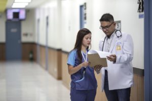 Two doctors looking at a chart in a hospital hallway. 