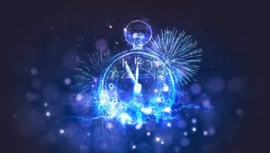 A photo of a glowing analog clock that’s about to strike midnight. It is surrounded by glowing white lights and white and blue fireworks against a black sky. 