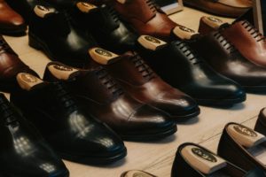 About a half dozen pairs of dress shoes neatly polished and sitting in tidy rows on a wooden surface. They have shoe horns inside of them, too, to help them keep their shape. 