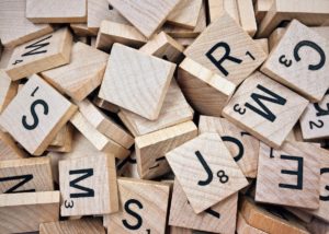 Closeup photo of an assortment of Scrabble tiles. They are a random grouping and do not spell any words, but you can see letters like r, j, m, and s included in the pile. 