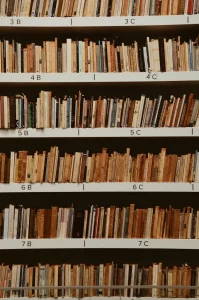 Four shelves of library books that are stacked neatly but with their spines facing away from the viewer. The shelves are labelled from 3B at the top left all the way down to 7C to the bottom right, although I do not know what those numbers and letters signify. 