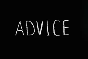 The word advice is written in block letters with chalk on a chalkboard. 