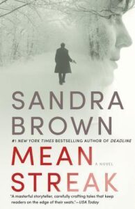 Book cover for Mean Streak by Sandra Brown. Image on cover shows a photo of someone wearing a long black winter jacket and walking outside in the snow on a foggy day. Superimposed on this image is the side view of a white woman’s face as she stares off thoughtfully into the distance, although we cannot see what she sees. 