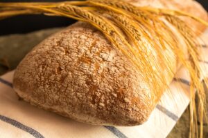 A few stalks of wheat lying gently on a loaf of bread.