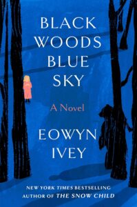 Book cover for Black Woods, Blue Sky by Eowyn Ivey. Image on cover shows two figures walking in the forest just after sunset when there is precious little light left. The one on the right and closer to the audience is wearing a black cape that obscures all of their features. The one on the left and further into the forest is bathed in light and wearing a peach dress or garment. I wonder where the light is coming from since everything else in this scene is so dark? 