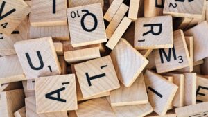 Closeup of scrabble tiles. Some are turned upside down, but you can see an a, q, t, and r tiles lying face up. 