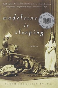 Book cover for Madeleine Is Sleeping by Sarah Shun-lien Bynum. Image on cover shows two young Victorian girls playing dress up. The one on the right is a preteen and is wearing a long white dress and a paper crown. The one on the left looks like she’s about six, is dressed as a knight, and is sitting on one end of a wooden seesaw. There is a leopard pelt - whether real or fake I cannot tell - lying on the floor between them. 