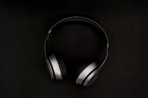 A shiny grey pair of over-the-ear headphones against a black background. 