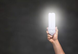 A person’s hand holding up a very bright lightbulb that does not appear to be attached to any power source! 