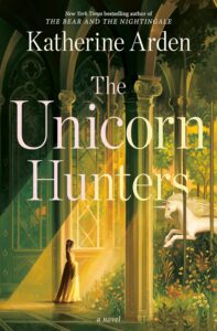 Book cover for The Unicorn Hunters by Katherine Arden. Image on cover is a painting of a white woman in a medieval-style flowing white dress standing in front of a multi-story window and looking out at what appears to be an ornate garden.