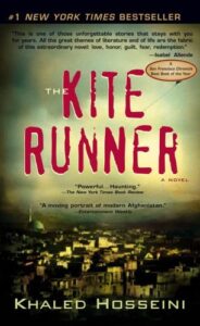 Book cover for The Kite Runner by Khaled Hosseini. Image on cover is a drawing of the city where the main character lived. The houses huddle close together and there are no plants to be seen anywhere. 