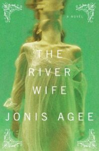 Book cover for The River Wife by Jonis Agee. Image on cover shows a white women with auburn hair floating in a river while wearing a gauzy white dress that is falling down her shoulders. 
