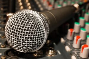 Closeup photo of a microphone lying on a soundboard, presumably in a recording studio. 