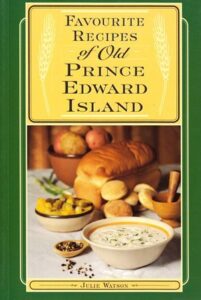 Book cover for Favourite Recipes of Old Prince Edward Island by Julie Watson. Image on cover shows a table ladened with delicious food like bread, roasted potatoes, and a creamy soup in a white bowl. They are all sitting on a white tablecloth. 