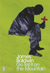 Book cover for Go Tell It on the Mountain by James Baldwin. Image on cover shows someone slumped over sitting as they hold a wooden cross in one hand. 