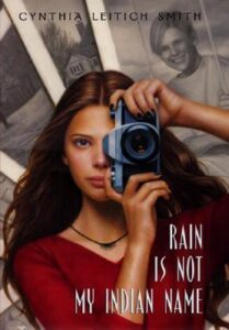 Book cover for Rain Is Not My Indian Name by Cynthia Leitich Smith. Image on cover shows a young native woman taking a photo. 