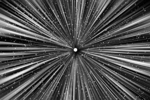 A computer-generated sketch of what warp drive might look like as a spacecraft suddenly zipped away. Hundreds of white lines are jutting out from a centralized space in the middle of the image, illuminating outer space for a moment as the spacecraft leaves. 