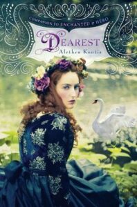 Book cover for Dearest (Woodcutter Sisters, #3; Books of Arilland, #4) by Alethea Konti. Image on cover shows a young brunette white woman with loosely curly hair who is wearing a blue dress and sitting on the ground while looking back at the viewer with a solemn expression on her face. She’s wearing a crown of purple and white flowers in her hair. 