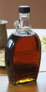 A bottle of Quebec maple syrup in a glass container. It’s sitting on a wooden table, presumably ready to be poured on some food!