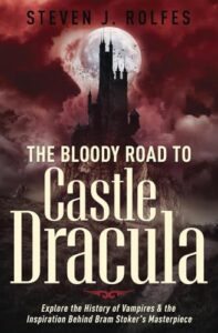 Book cover for The Bloody Road to Castle Dracula - Explore the History of Vampires & the Inspiration Behind Bram Stoker's Masterpiece Author: Steven J. Rolfes. Image on cover shows a drawing of a castle on top of a hill. A full moon looms large behind the castle, and the sky is a disturbing shade of blood red. 
