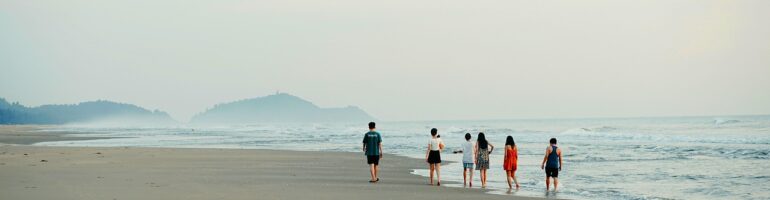 Several friends walking down the beach together on a foggy day. This shot was taken from far away and behind, so no facial features can be discerned.