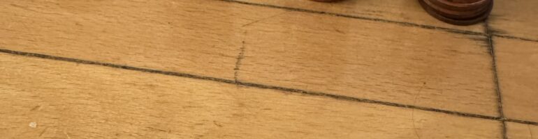Closeup shot of four stacks of various amounts of pennies on a wooden floor.